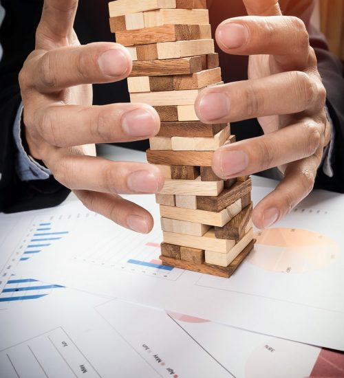 Planning, risk and strategy in business concept, businessman gambling placing wooden block on a tower.